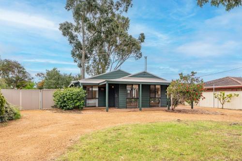 a green house with a fence and a yard at Chrissie's Cottage in Dunsborough