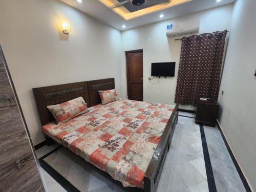 a bedroom with a bed with a quilt on it at Guest House & Apartments Johar Town near Emporium & Expo in Lahore