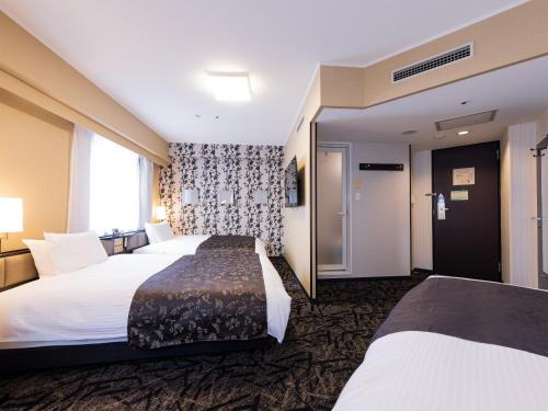 a hotel room with two beds and a window at APA Hotel Kokura Ekimae in Kitakyushu