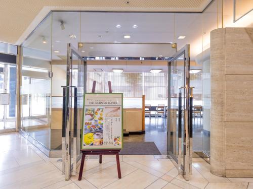 Un ascensor de cristal en un edificio con un cartel en él. en APA Hotel Kokura Ekimae, en Kitakyushu