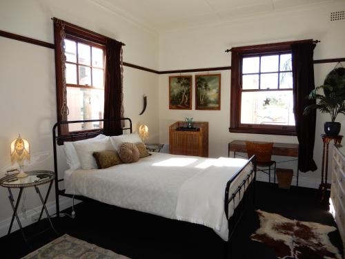 a bedroom with a large bed and two windows at Women Only Guesthouse in Mullumbimby