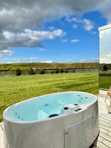 a hot tub on a deck with a view of a field at Nest Retreat Iceland - Mirror Houses by the Rangá river in Hella