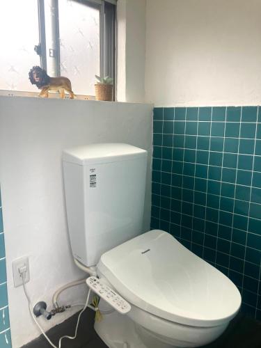 a toilet in a bathroom with a dog sitting on a window at お宿イヌとネコと in Shima