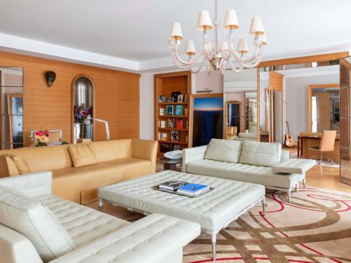 ein Wohnzimmer mit weißen Möbeln und einem Kronleuchter in der Unterkunft Hôtel Le Royal Monceau Raffles Paris in Paris