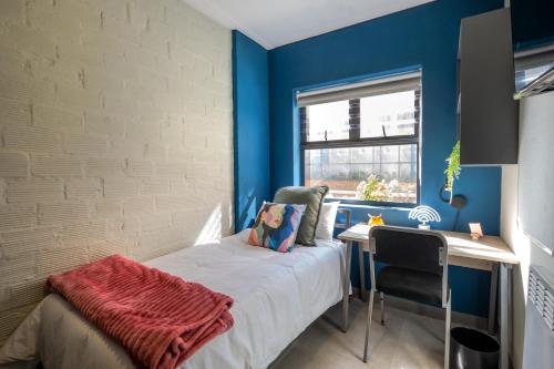 a bedroom with blue walls and a desk and a bed at Peak Studios Cape Town in Cape Town