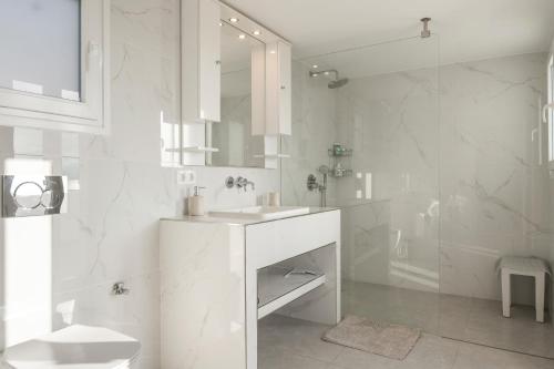 a white bathroom with a sink and a shower at Aegean Villas Ios in Ios Chora