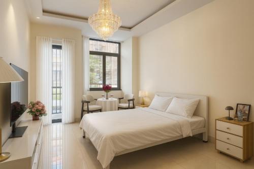 a bedroom with a white bed and a chandelier at The Writeriana de Lumière in Ho Chi Minh City