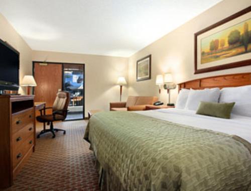Habitación de hotel con cama grande y escritorio. en Ramada by Wyndham Des Moines Tropics Resort & Conference Ctr, en Urbandale