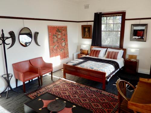 a bedroom with a bed and a chair and a table at Women Only Guesthouse in Mullumbimby