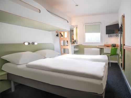 a bedroom with a large white bed and a desk at B&B Hotel Lübeck Berliner-Platz in Lübeck
