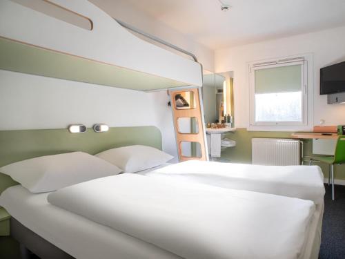 a bedroom with a large white bed and a desk at B&B HOTEL Flensburg-City in Flensburg