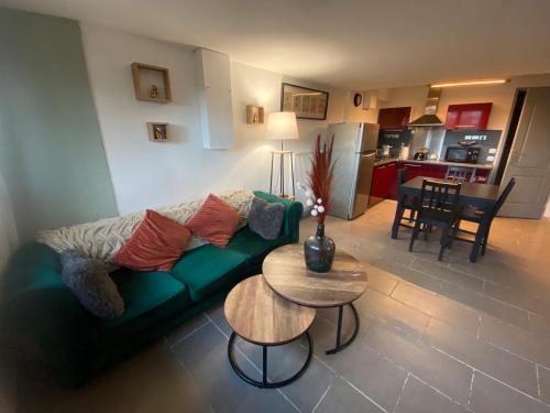 a living room with a green couch and a table at Le Jardin de Sasha et La Noisette in Équemauville