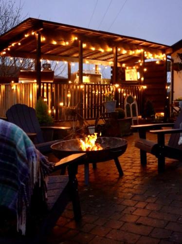 a patio with a fire pit and a building with lights at 3-Country retreat with outdoor kitchen and pizza oven! in Pont Sticill
