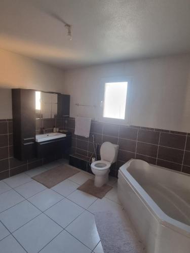 a bathroom with a tub and a toilet and a sink at Maison plein-pied 8 pers avec piscine sur demande in Thiers