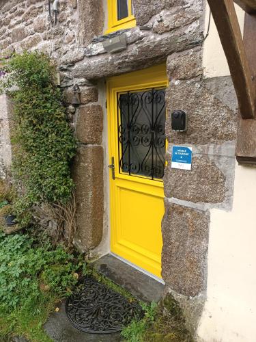a yellow door on the side of a stone building at "La Maison de Poupée" Gîte cosy Monts d'Arrée proche Huelgoat Bretagne in Berrien
