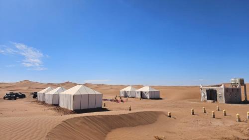 un grupo de tiendas blancas en el desierto en Bivouac Le secret des dunes, en Foum Zguid