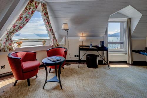 a room with a bed and a desk and two chairs at Romantik Hotel Mont Blanc au Lac in Morges