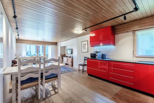 a kitchen with red cabinets and a dining table at Prada Laax by Quokka 360 - Alpine Residence with Shared Sauna in Laax