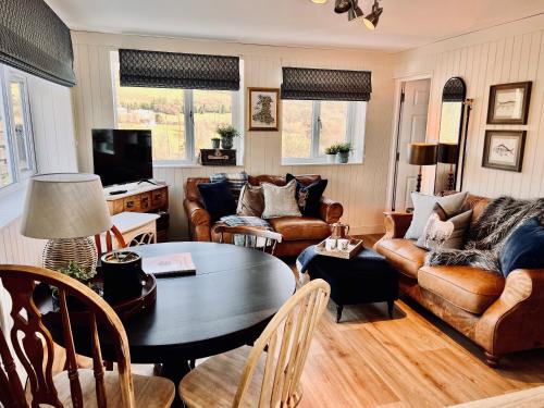 a living room with leather furniture and a table at 3-Rustic Escape, Firepit, BBQ & Pizza Oven in Pont Sticill