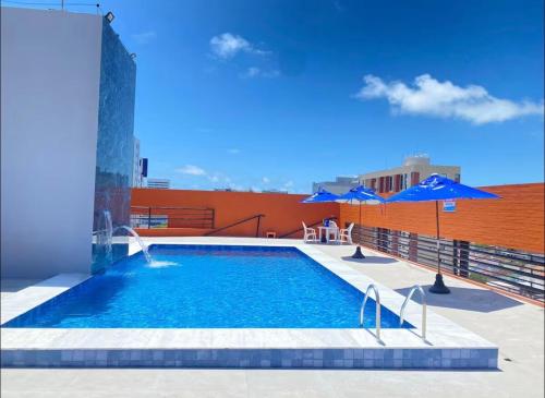 - une piscine avec des parasols bleus au-dessus d'un bâtiment dans l'établissement Flat Completo - Praia de Jatiuca, à Maceió
