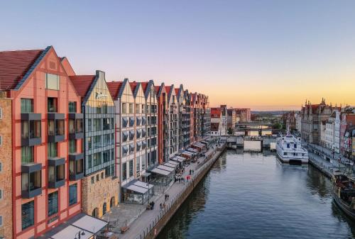a view of a river with buildings and boats at DEO PLAZA Apartments & Riverside by Downtown Apartments in Gdańsk