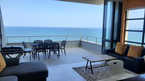 a balcony with tables and chairs and a view of the ocean at Stunning Luxury Penthouse at 30 Degrees, Umdloti Beachfront in Umdloti