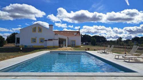 eine Villa mit einem Swimmingpool vor einem Haus in der Unterkunft Villa das Oliveiras in Grândola