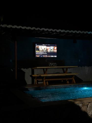 a dark room with a table and a television at Bangalô raizes in São Gonçalo do Amarante
