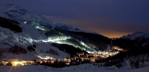 a view of a snowy mountain with a city at night at Lo chalet di Lucky in Campodolcino