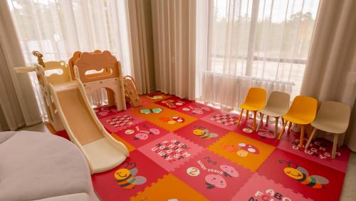 a childs room with a crib and chairs on a colorful floor at Центр семейного отдыха Bravo Burabay in Kotarkol