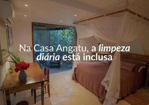 a bedroom with a canopy bed and a table at Casa Angatu in Trancoso