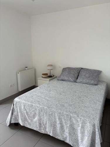 a bedroom with a large bed with a white wall at L'R de Malo studio cosy in Dunkerque