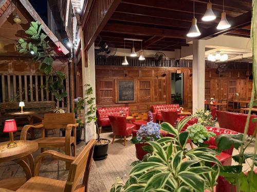 a restaurant with red chairs and tables and plants at Khom Chiang Mai in Chiang Mai