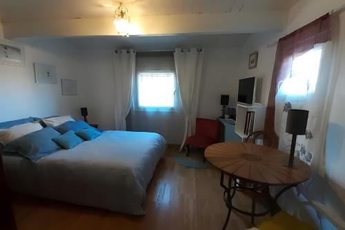 a bedroom with a bed and a table and a window at Au Jardin Des Couleurs in Pierrefeu-du-Var