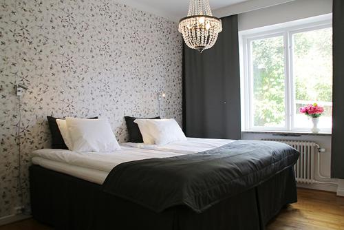 een groot bed in een slaapkamer met een kroonluchter bij Apartment Hotell Conrad in Karlskrona