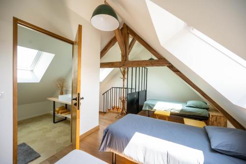 a attic bedroom with a bed and a window at Les GRANDS enfants - 1h15 de Paris - Piscine intérieure chauffée - Offres Pro in Subligny
