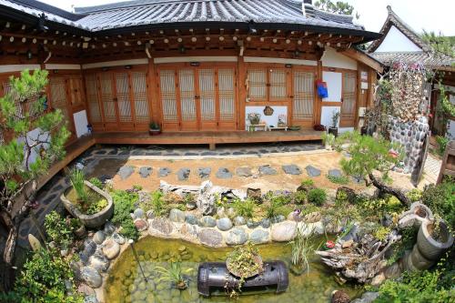 an asian style house with a pond in front of it at Happiness Full Hanok Guesthouse in Jeonju