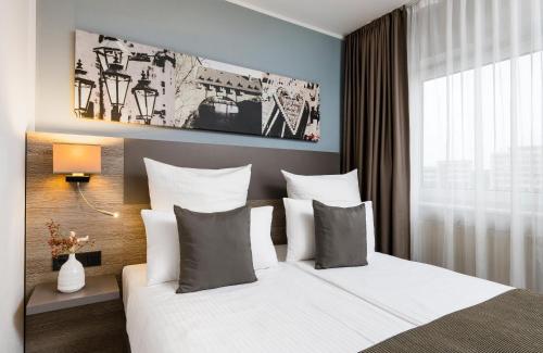 a bedroom with a large bed with white sheets and pillows at Leonardo Hotel Nürnberg in Nürnberg