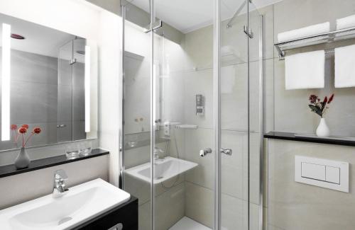 a bathroom with a glass shower and a sink at Leonardo Hotel Nürnberg in Nürnberg
