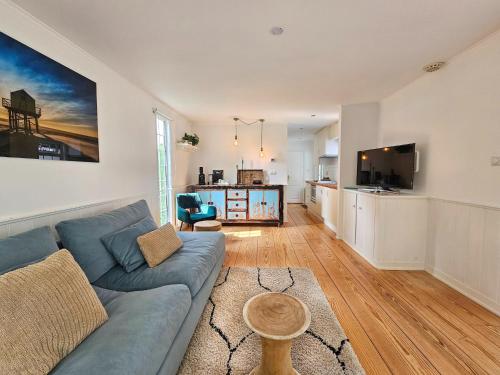 a living room with a blue couch and a kitchen at Chalet Kieftveen with hot tub for four Person in Voorthuizen
