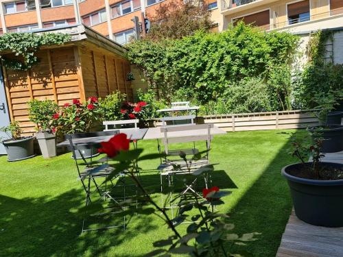 a garden with a table and chairs on the grass at La Maison V.H., Appartements d'Hôtes in Troyes