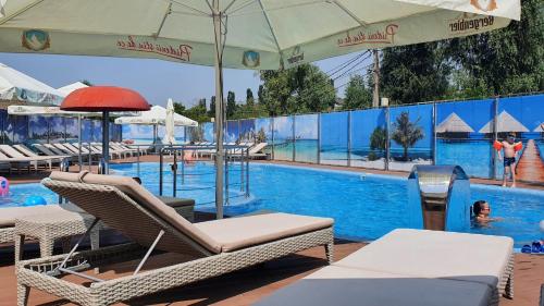 a pool with chairs and an umbrella and a swimming pool at Poiana Bradului Complex Hotelier & Restaurant in Chişinău