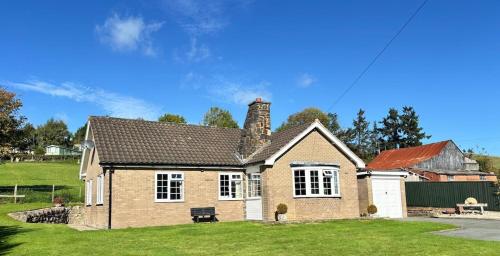 a small brick house with a grass yard at Ty Newydd in Llangyniew