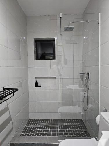 a white bathroom with a shower with a television in it at Bilene Harmony Home in Vila Praia Do Bilene