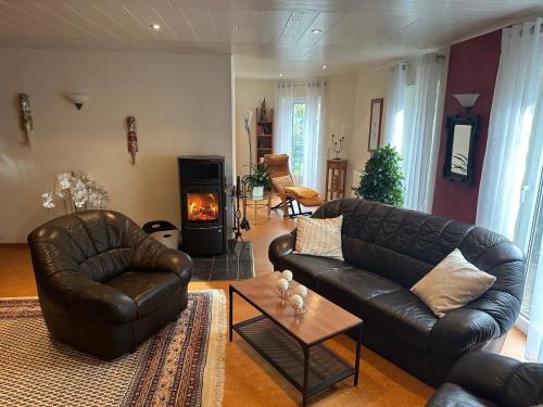 a living room with two leather couches and a fireplace at Ferienwohnung Riva in Kronau