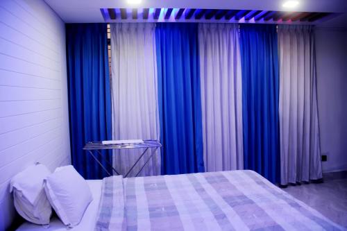 a bedroom with blue and white curtains and a bed at Hotel Blue Castle International Two in Pāksey