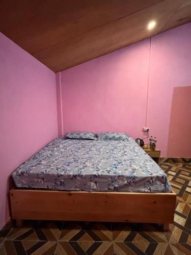een bed in een kamer met een roze muur bij Ghumakkad Homestay in Harsil