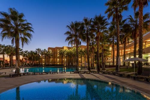 Una piscina con palmeras y un edificio. en NAU Sao Rafael Suites - All Inclusive, en Albufeira