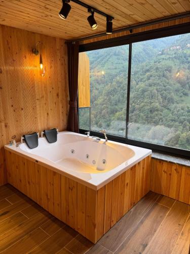 een groot bad in een kamer met een groot raam bij Foresta Suit Bungalov in Ardeşen