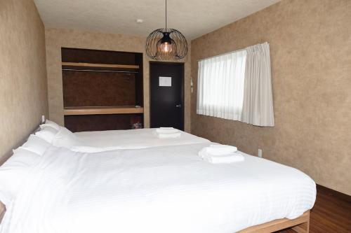 a large white bed in a bedroom with a chandelier at Darin博多 in Fukuoka